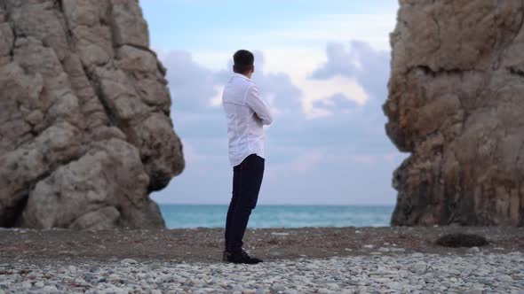 Young Man Look Around Between Two Mountains on the Seaside Where Waves Beats on Rocks. Cyprus