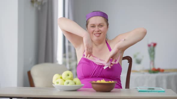Fat Young Caucasian Woman Breaking Free From Measuring Tape on Hands Eating Chips Making Strength