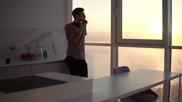 Tall Young Single Man with Headphones on Neck Relaxing By the Window at Studio Kitchen Watching