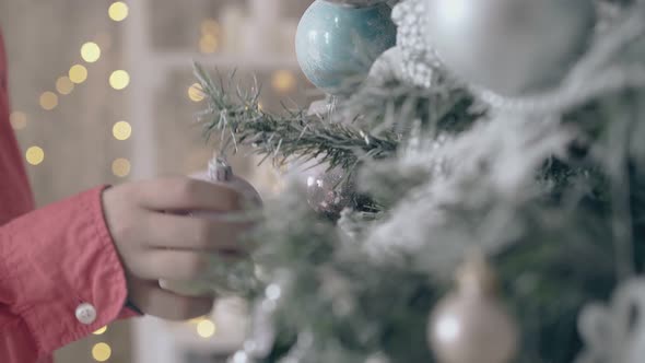 Kid Touches Christmas Decoration Hanging on New Year Tree