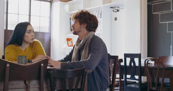 Two Young People Talking at Cafe Table While Waiting to Order