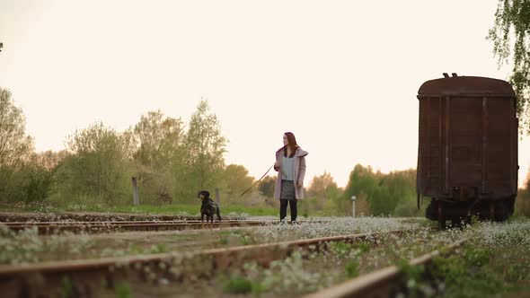 Young Woman Walks at Camera with Her Dog at Old Abandoned Railway
