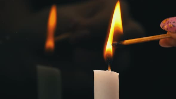 White Paraffin Candle is Lit with a Match on a Black Background in Reflection