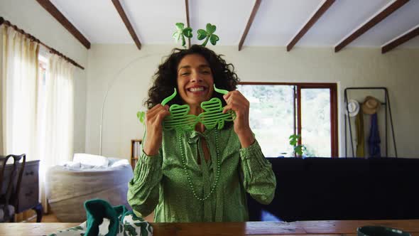 Portrait of mixed race woman wearing green glasses and costume at home