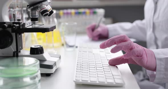 Gloved Hands Typing on Computer Keyboard in Laboratory
