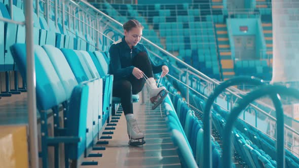 Young Lady is Lacing Up Her Skates in the Sports Arena