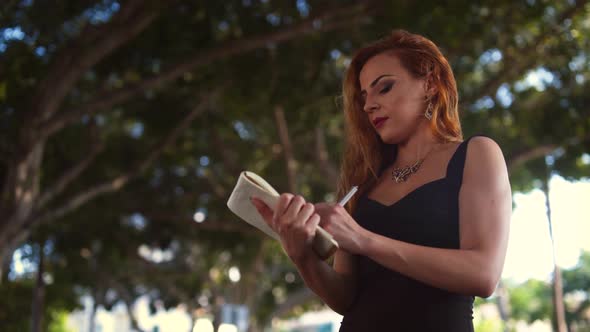 Young Elegant Businesswoman Writing Notes in Personal Organizer in City