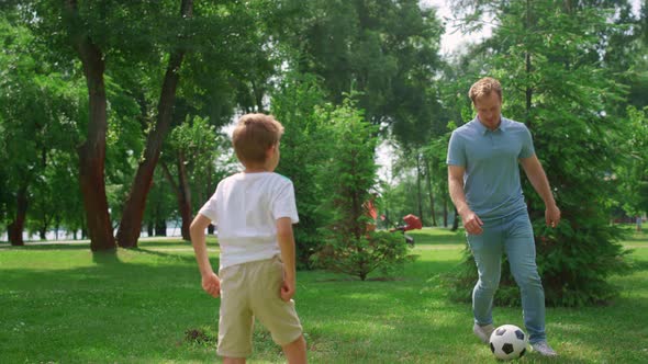 Father Play Football with Son on Green Lawn Closeup