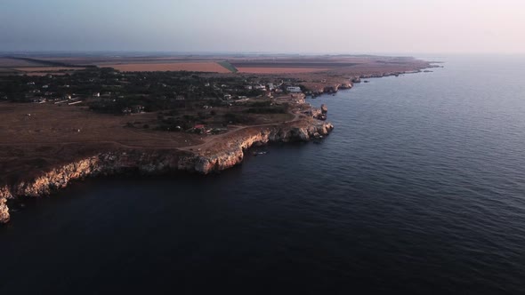 Drone top down aerial view of waves splash against rocky seashore, background. Flight over high clif