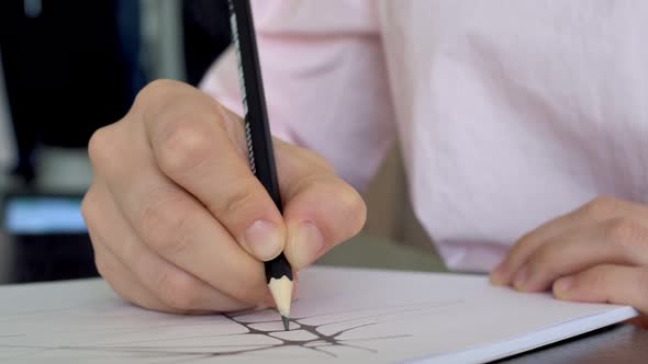 Closeup of a Pencil in the Hand of the Designer Draws Lines on Paper Creates a Sketch for a Future