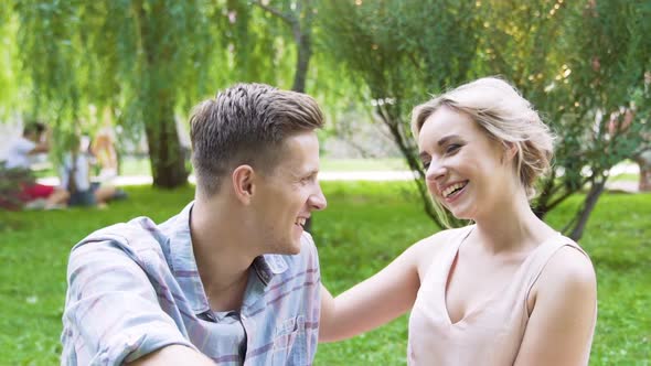 Tender young married couple sitting in green park, happy relationship, slow-mo