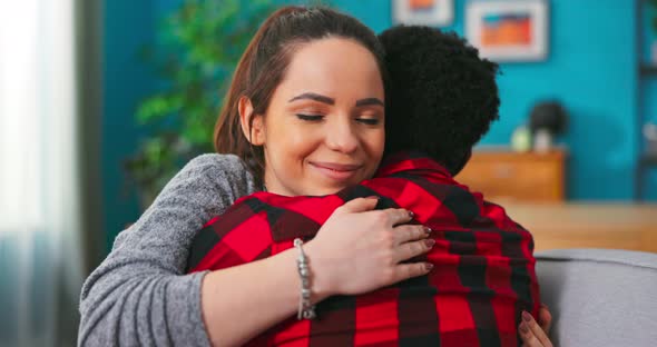 Smiling Happy Couple African Man and American Woman Girl Hugging While Sitting on Sofa at