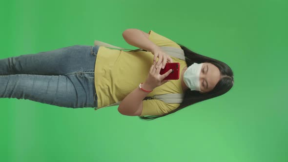 Asian Girl Student Wearing A Mask And Use Mobile Phone While Walking To School On Green Screen