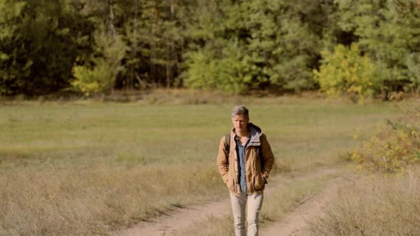 Tourist Hiker Man in Forest with Backpack, Walking in Woods at Autumn.