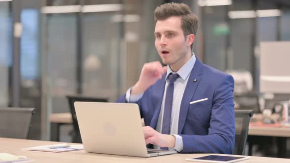 Businessman Coughing While Using Laptop in Office