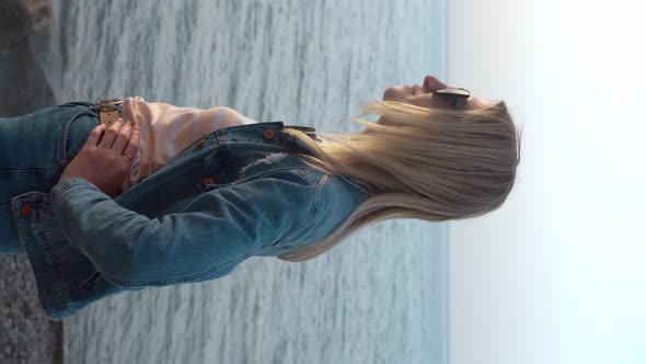 beautiful girl in sunglasses enjoys sea wind and sunset on beach.