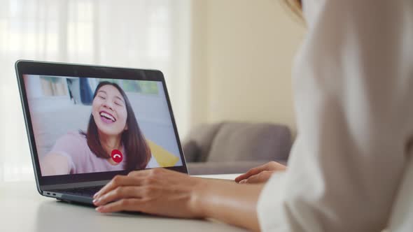 Asian business female using laptop video call talking with friends while working from home.