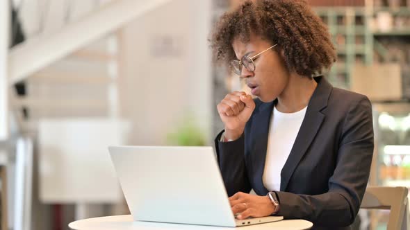 Sick African Businesswoman with Laptop Coughing at Cafe 