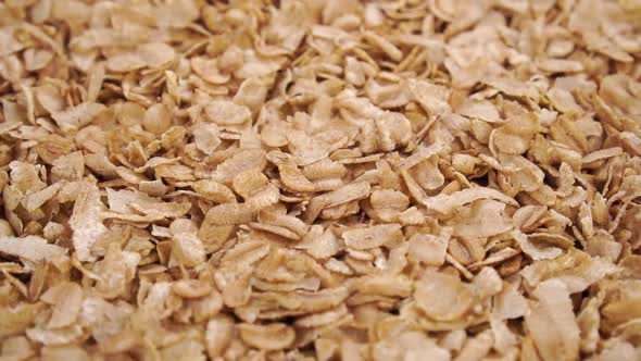 Dry wheat spelt flakes. Falling uncooked breakfast cereal in slow motion. Close up