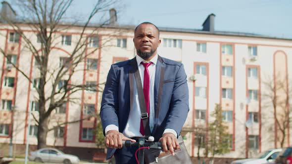Portrait of Confident Black Businessman Riding Escooter