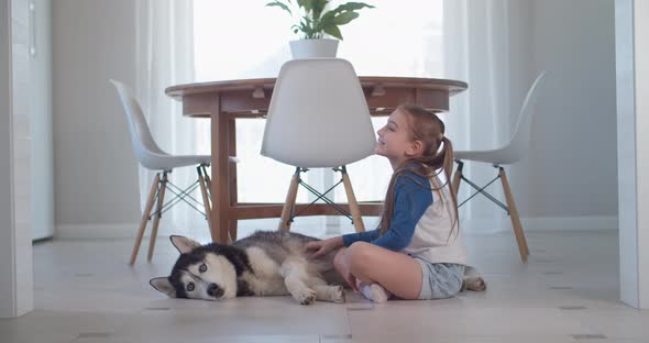 Girl Stroking Her Purebred Dog While Lying on the Floor in a Modern Apartment