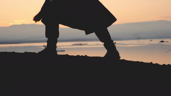 Man In Boots Walking Through Cold Sunset Landscape