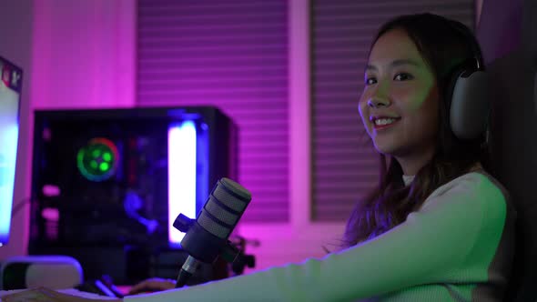 Asian gamer playing online video game winning excited on PC with lighting effect