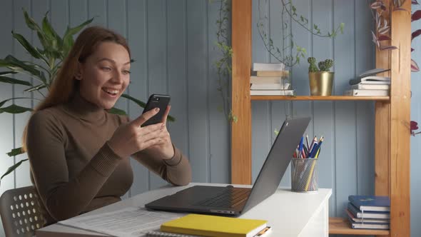 Woman Sit at Desk Read Message on Smart Phone Feels Excited Incredible Happy