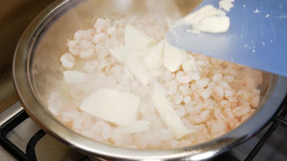 Pouring fresh butter on small shrimps cooking in steamy pot