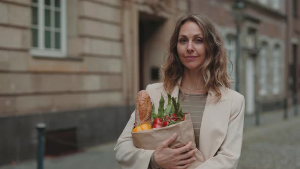 Mature Lady Standing on Street with Grocery Bag in Hands