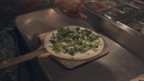 a pizza chef places toppings on a neapolitan style pizza at a restaurant