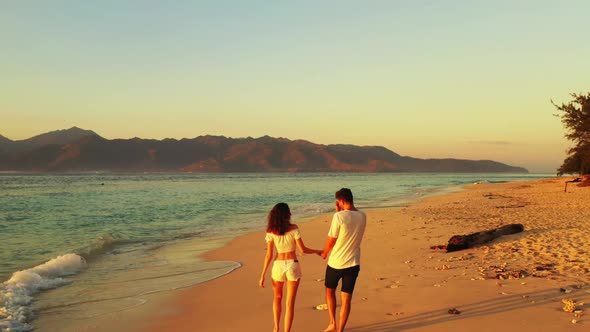 Guy and girl happy together on beautiful lagoon beach journey by transparent lagoon with white sand 