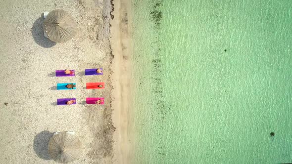 Aerial view of yoga group on mats on beach with parasols.