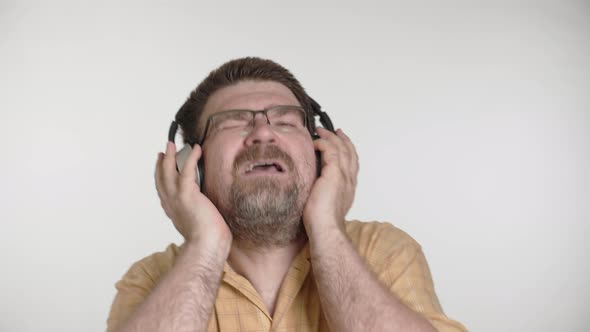 Caucasian man enjoy listen to fast rhythmic music by wireless silver headphones at home.