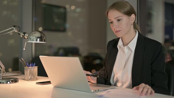 Businesswoman Working on Laptop and Document in Office at Night 