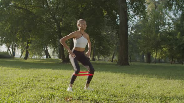 Sporty Woman Doing Squats Wiith Resistance Band