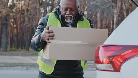 Elderly African American Male Courier in Uniform Takes Goods Outdoors Mature Delivering Worker