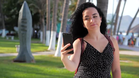 Young Traveler a Brunette Woman or Girl Making Selfies on a Sunny Day Against the Background of Palm