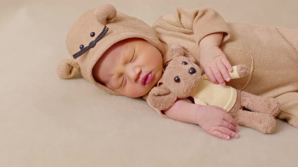 happy newborn baby weaing cute Mouse costume lying sleeps and hug doll on Beige background