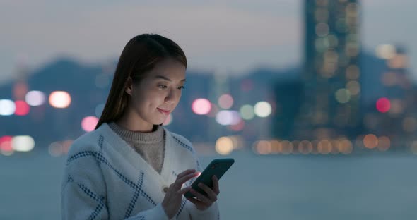 Woman use of mobile phone in city at night