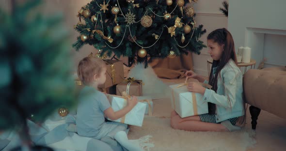 Children Open Christmas Gifts Under the Tree