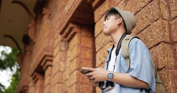 Traveler man typing on phone while standing at ancient temple