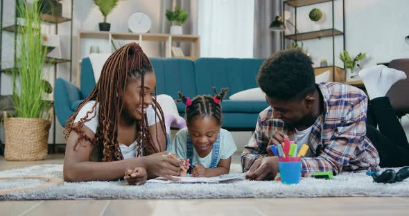 African Couple Drawing with Daughter on Floor