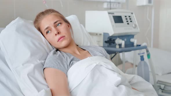 A Sick Young Woman Lying in a Hospital Bed and Waiting a Doctor