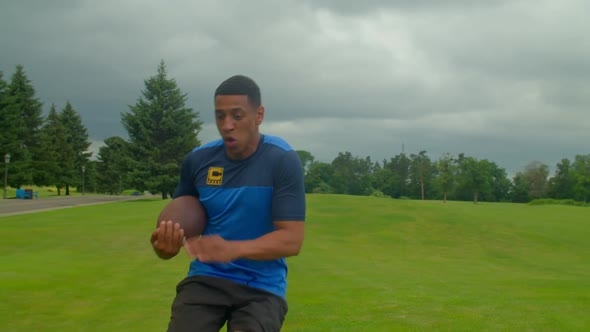 Active Fit Black American Football Player with Ball Passing By Defender on Field