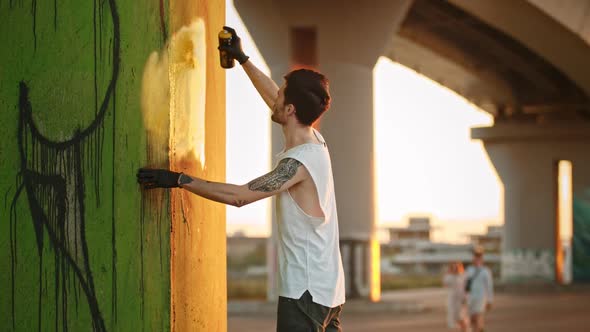 A Creative Man Standing Near the Wall and Painting a Graffiti with a Paint