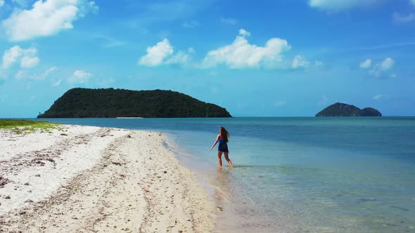 Female models happy and smiling on tranquil resort beach adventure by shallow lagoon and white sand 