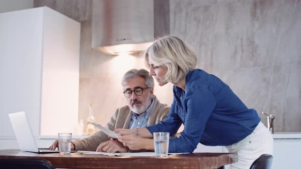 Slow motion shot of mature couple using laptop and checking documents