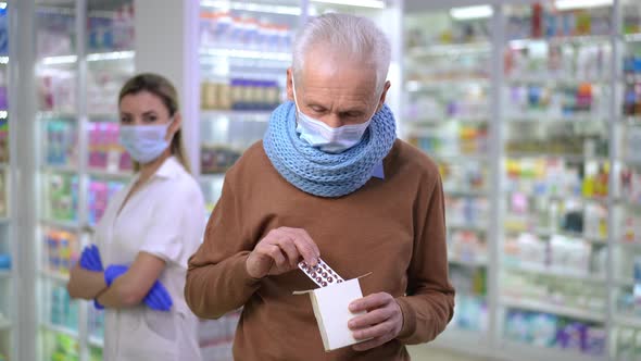 Portrait of Happy Senior Man Advertising Pills Standing in Covid19 Face Mask in Pharmacy with