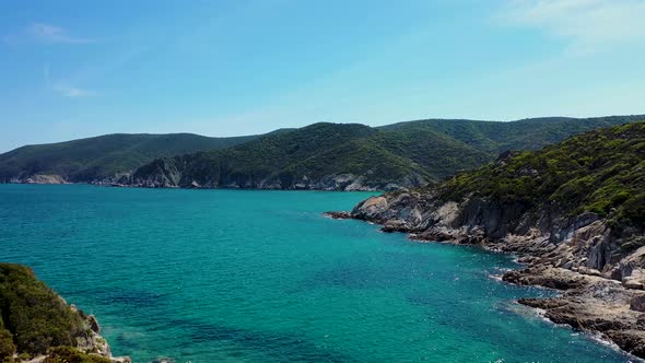 Aerial view of turquoise blue crystal clear water and rocky coast line with island view discovering